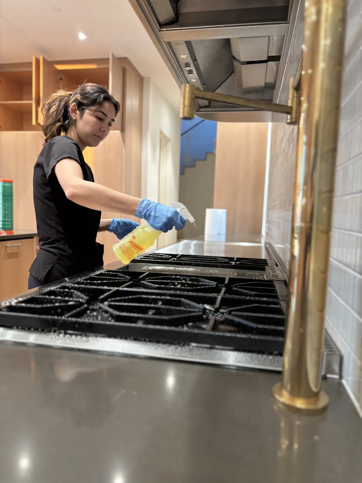 Fresh Start crew member spraying down a gas cooktop during a Nashville deep clean