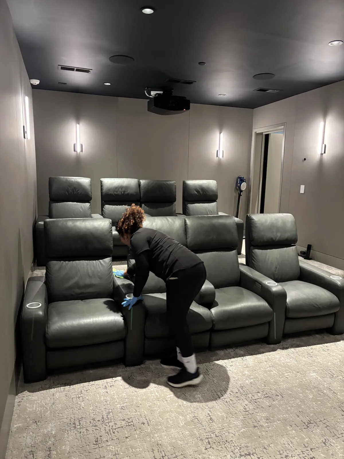 Fresh Start crew member wiping down the leather seating in a Nashville getaway home media room