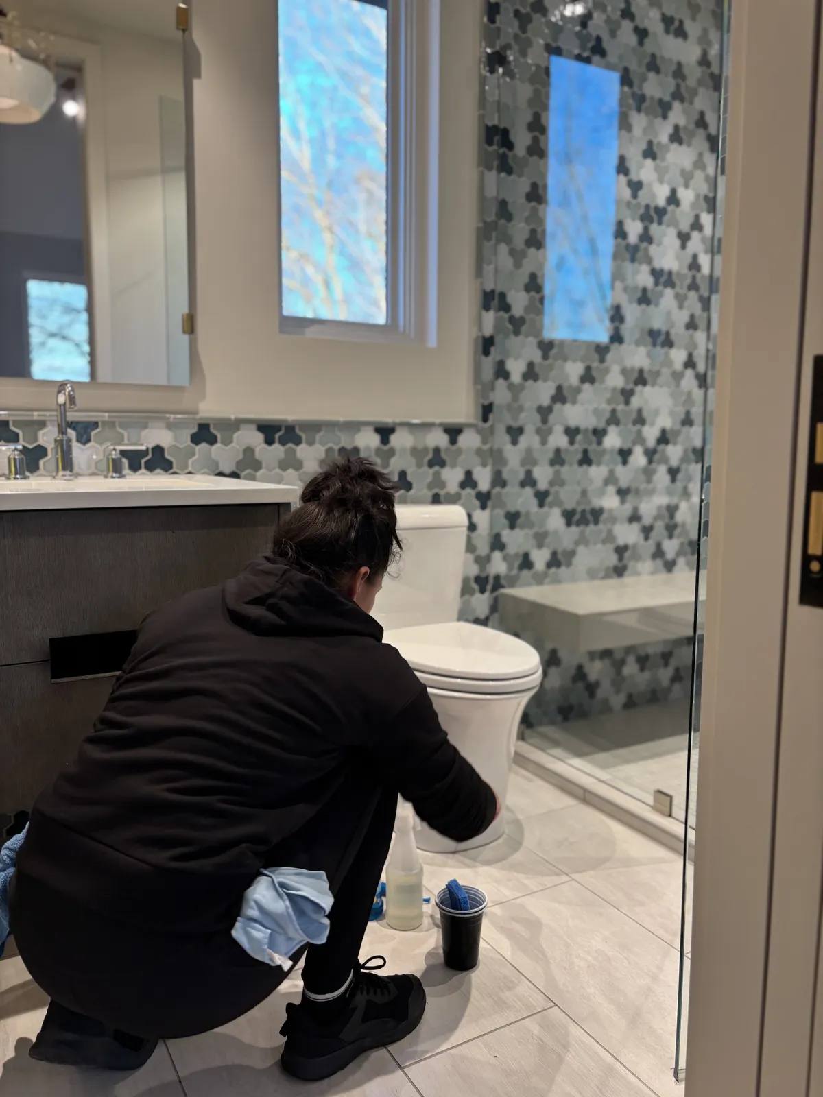 Fresh Start crew member cleaning around the toilet and tiled shower in a bright Nashville bathroom