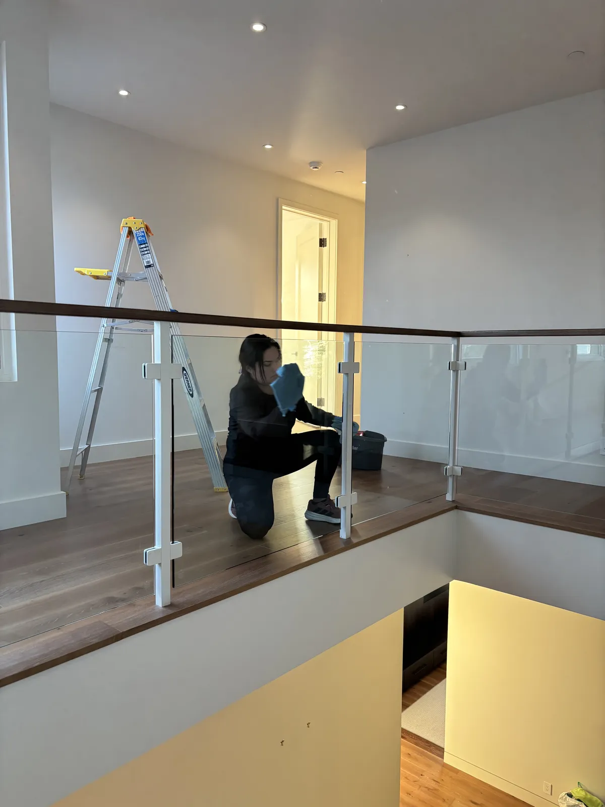 Fresh Start crew member cleaning a glass stair railing in an empty Nashville home during a move-out clean