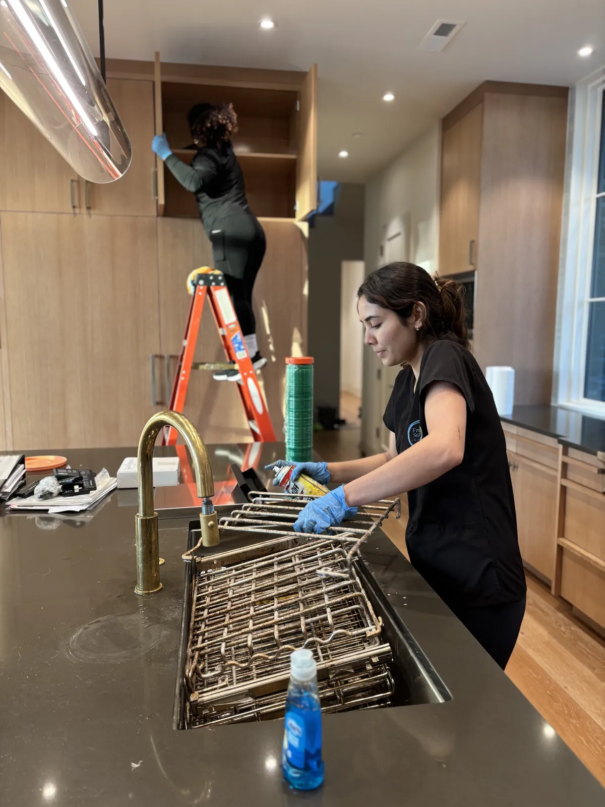 Fresh Start crew detailing upper cabinets and soaking oven grates in the sink during a Nashville kitchen deep clean