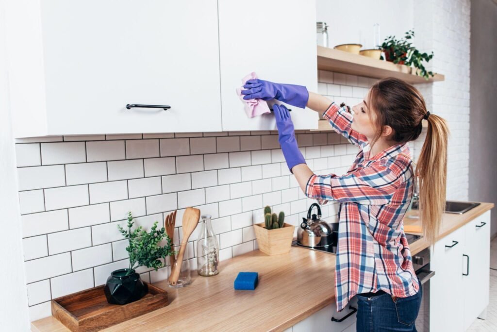 Woman wiping kitchen cabinets during kitchen deep cleaning