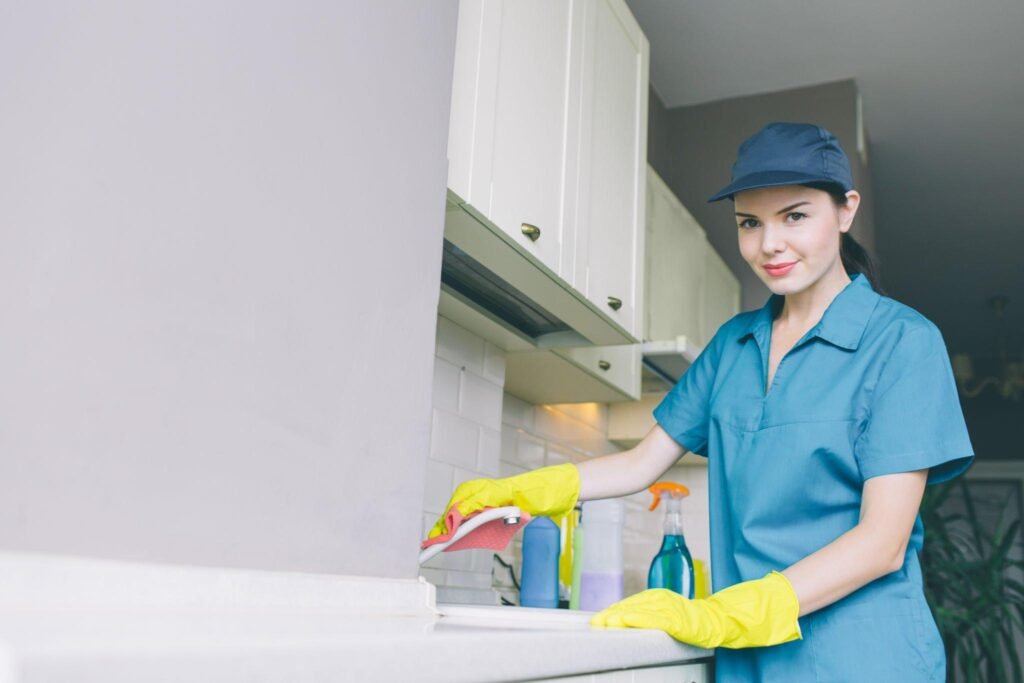 Professional cleaner wiping kitchen counter in apartment