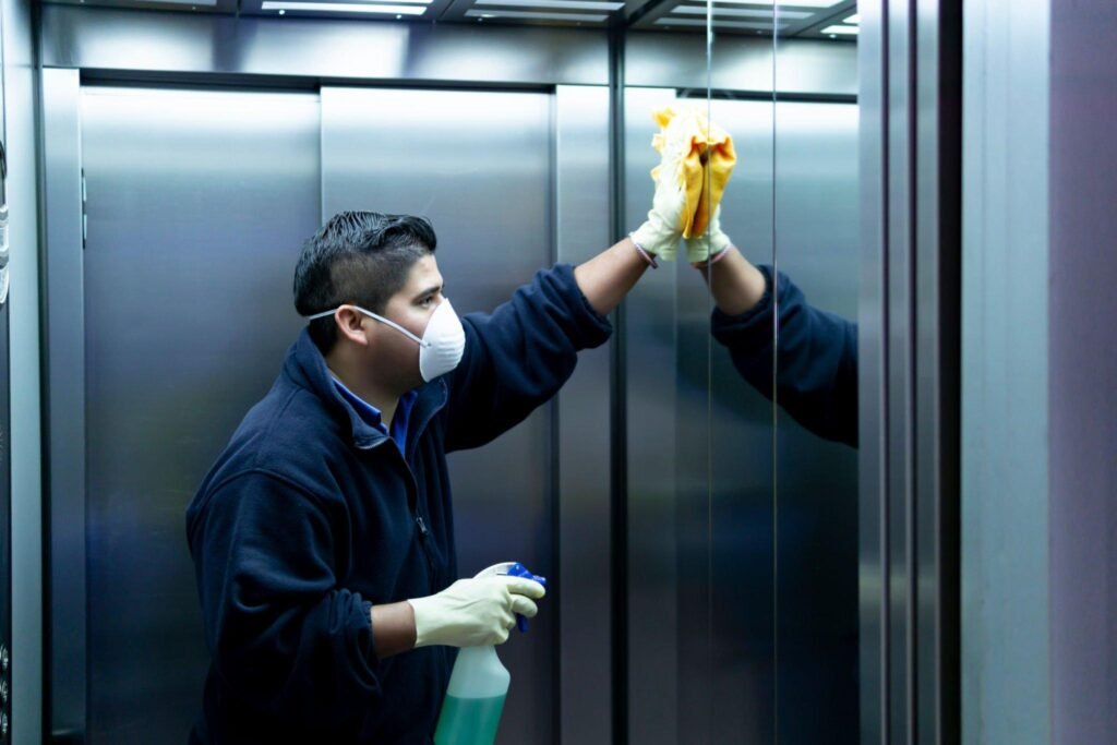 Janitor sanitizing elevator doors with spray and cloth