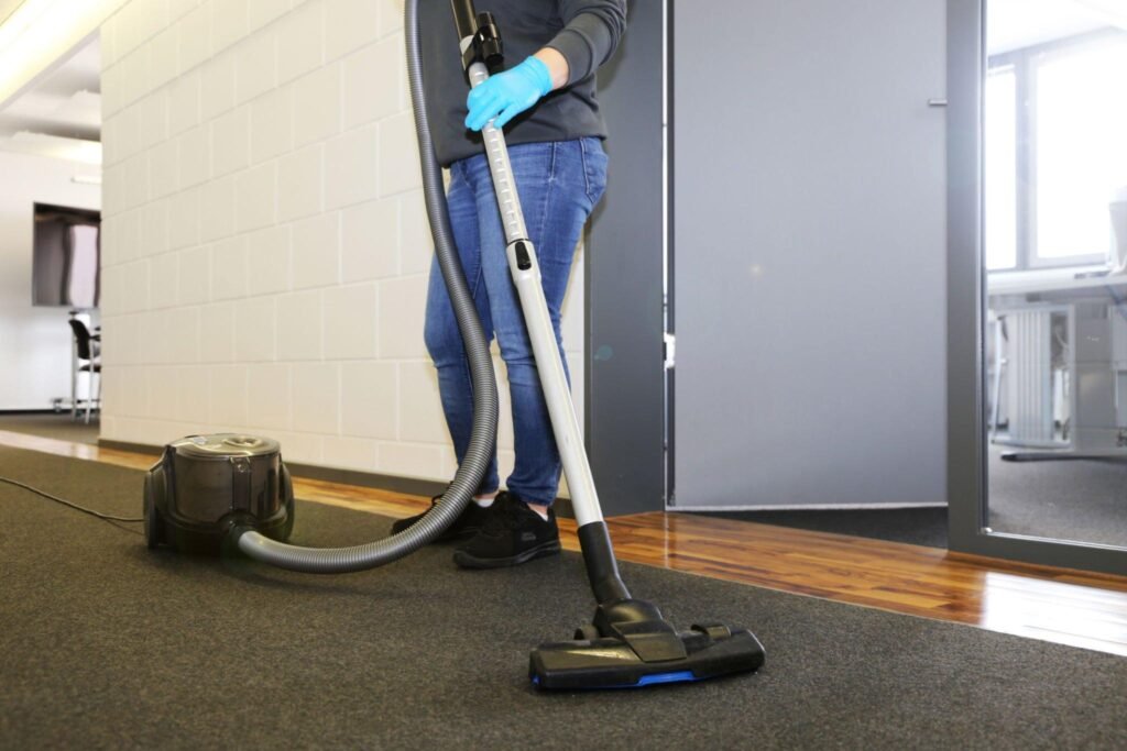 Janitor vacuuming commercial carpet after demolition cleanup