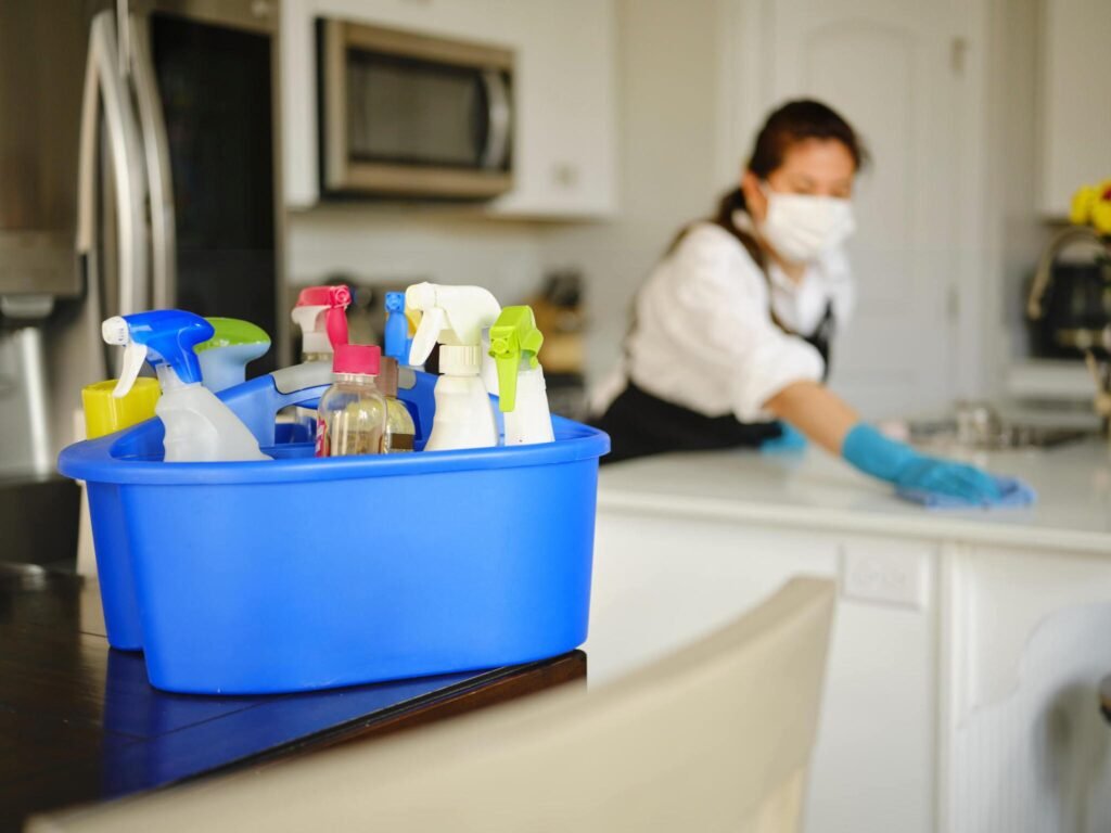 Cleaning supplies caddy with worker sanitizing kitchen in background