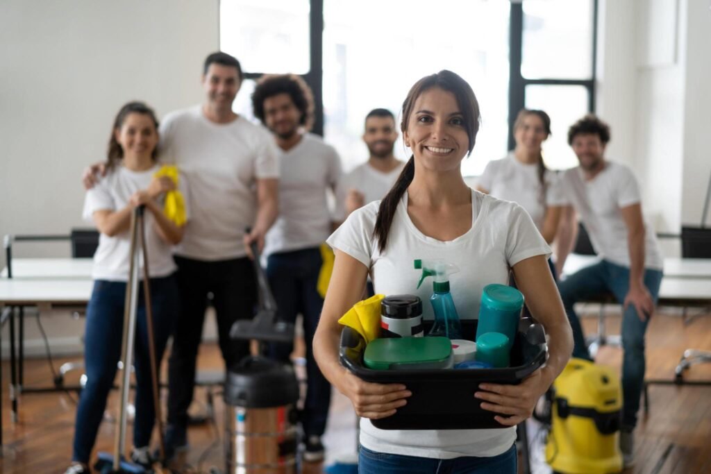 Cleaning team leader holding supplies with volunteers behind her