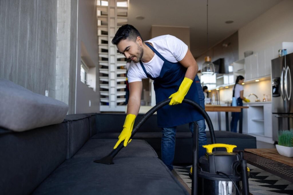 Man vacuuming couch upholstery after construction debris removal