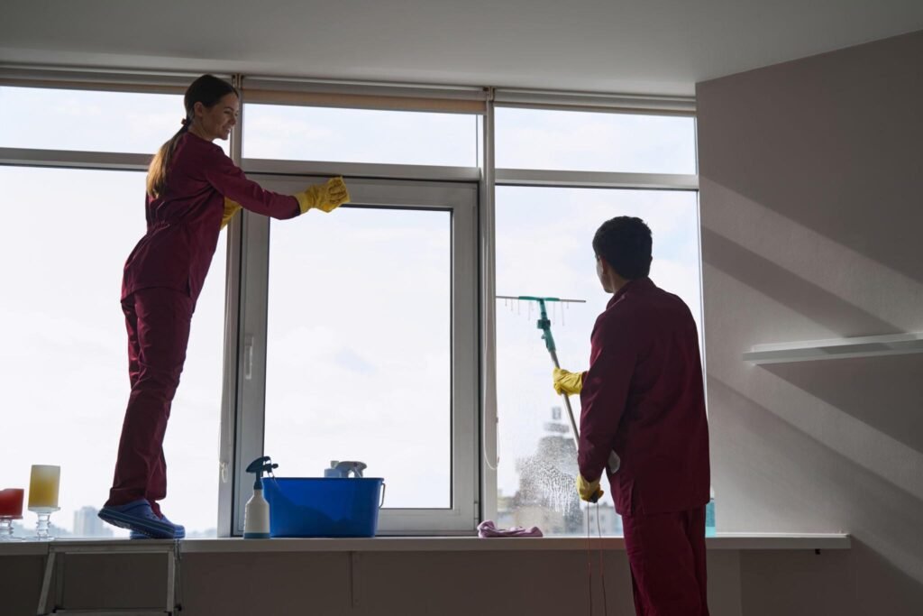 Two cleaners washing large windows during phase clean