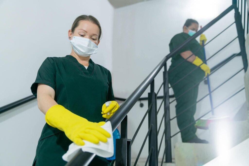 Two cleaners sanitizing stairway railings during final clean