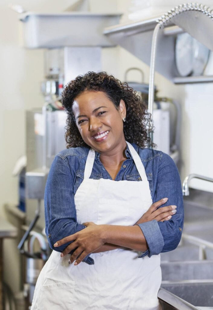 Smiling kitchen worker standing in clean commercial kitchen