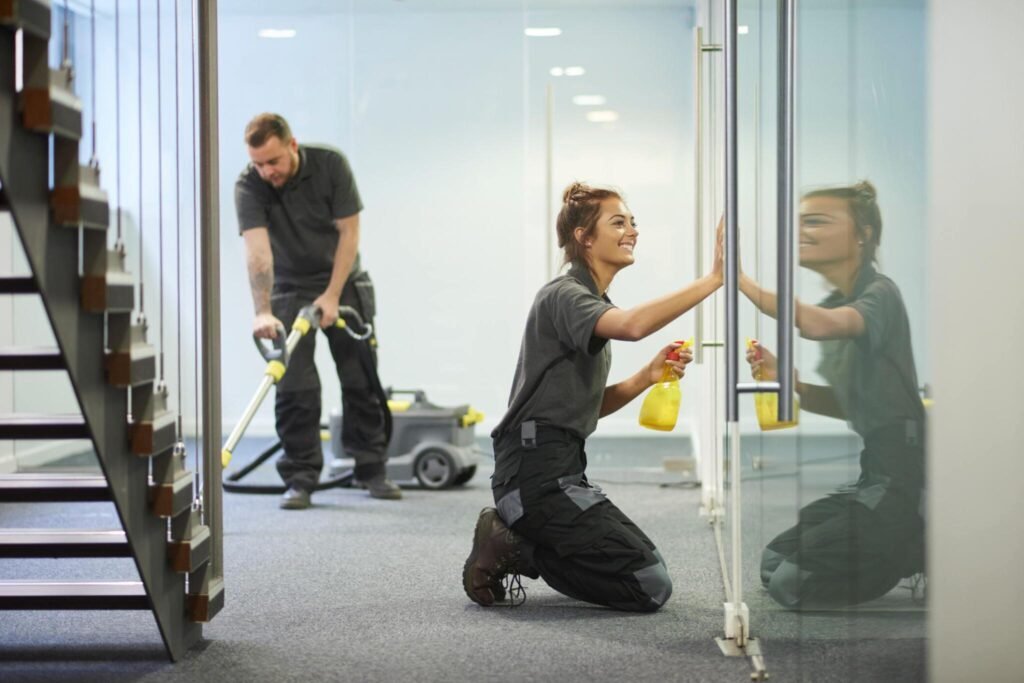Cleaning crew wiping glass doors and vacuuming new construction site