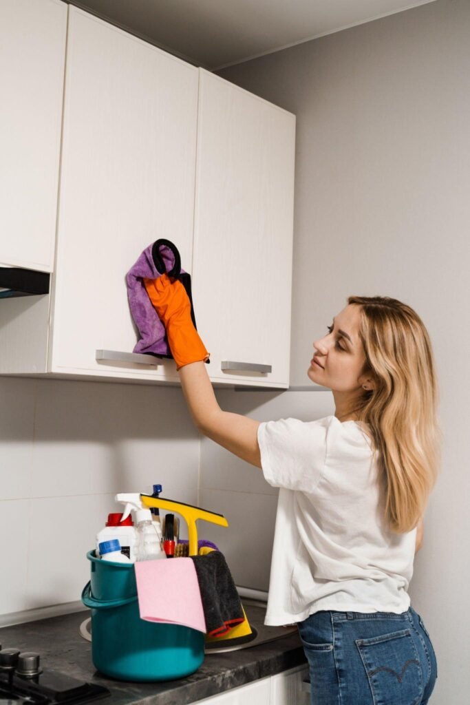 Woman wiping kitchen cabinets with cloth during renovation cleanup