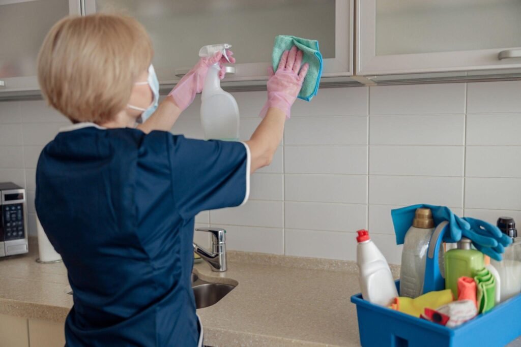 Cleaner wiping kitchen cabinets after post-construction dust