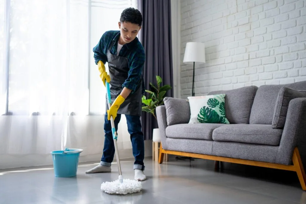 Man mopping living room floor with bucket and mop